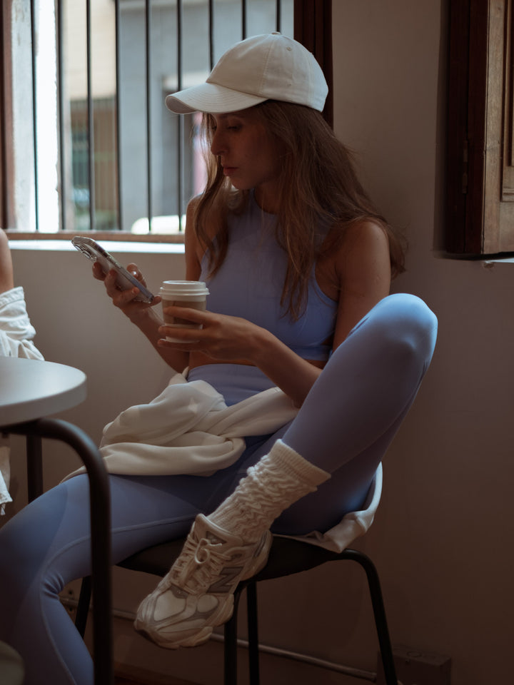 Modelo sentada tomando café con un conjunto deportivo color azul