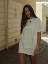 Modelo usando camiseta crudo básica con mini vestido crudo.