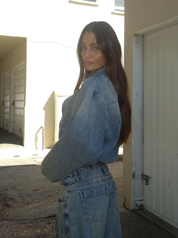 Vista lateral de modelo usando chaqueta bomber denim con jean.