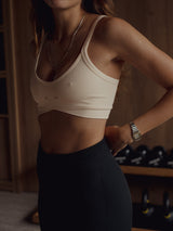 Modelo usando top deportivo crema de tiras con corte asimétrico.