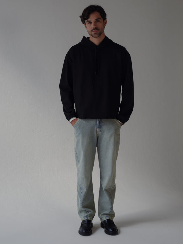 Modelo usando buzo negro con jean azul ahumado y zapatos negros.