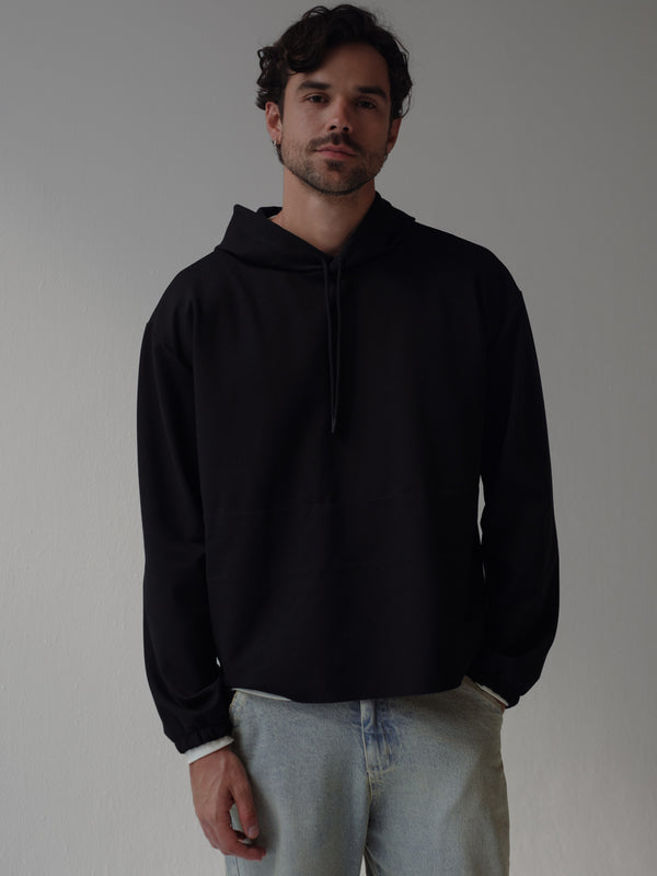 Modelo usando buzo negro con jean azul ahumado.