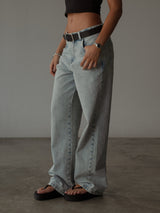 Modelo usando jean clásico azul bota recta con cinturón, sandalias y top.