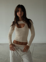 Modelo usando mangas deportivas crema sin costuras con ropa deportiva.