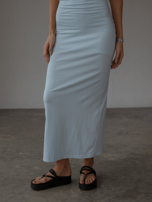 Vista de falda de vestido azul claro ajustado con sandalias negras.