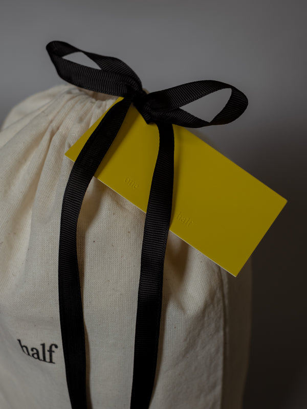 Detalle de cinta negra anudada en moño con tarjeta amarilla de regalo. 