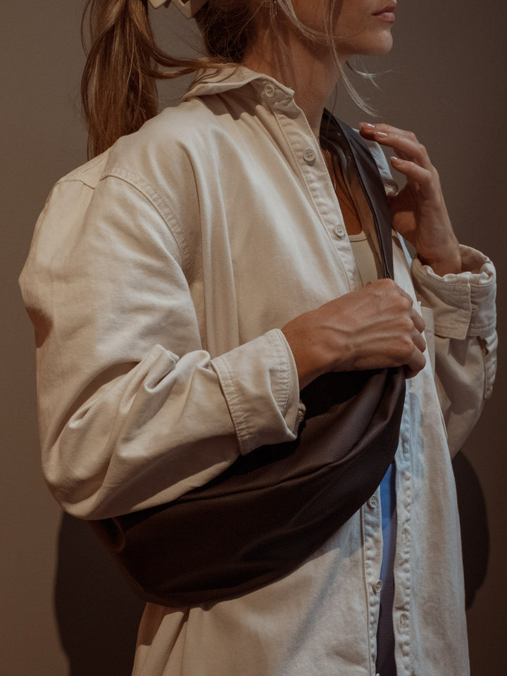 Modelo usando una camisa manga larga con un bolso color café