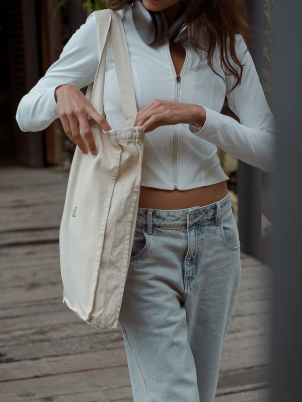 Mujer buscando dentro de un bolso color crema