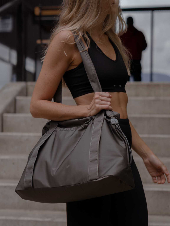Eugenia está usando crop top y leggings color negro con tote bag color gris.