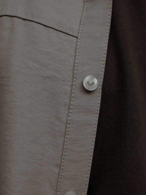 Detalle de los botones de una camisa manga corta color arena sobre una camiseta color café.