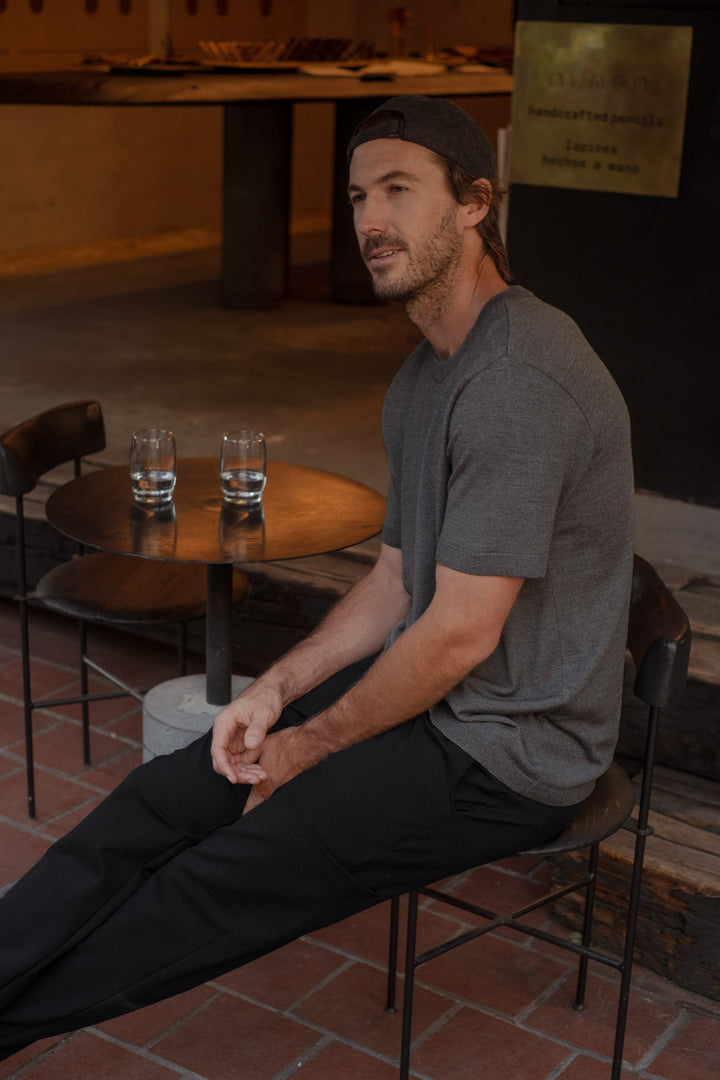 Modelo usando un pantalón negro, una camiseta básica color gris y una gorra