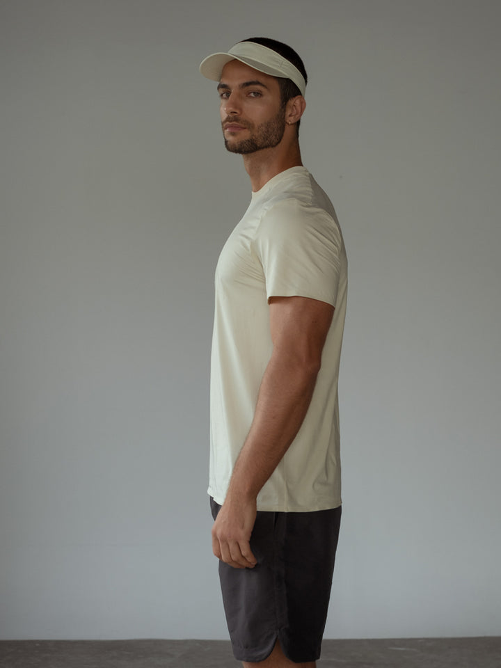 Modelo usando una visera y camiseta color crema y una bermuda.