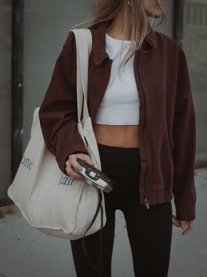 Front view of white crop top, brown cargo jacket and tote bag