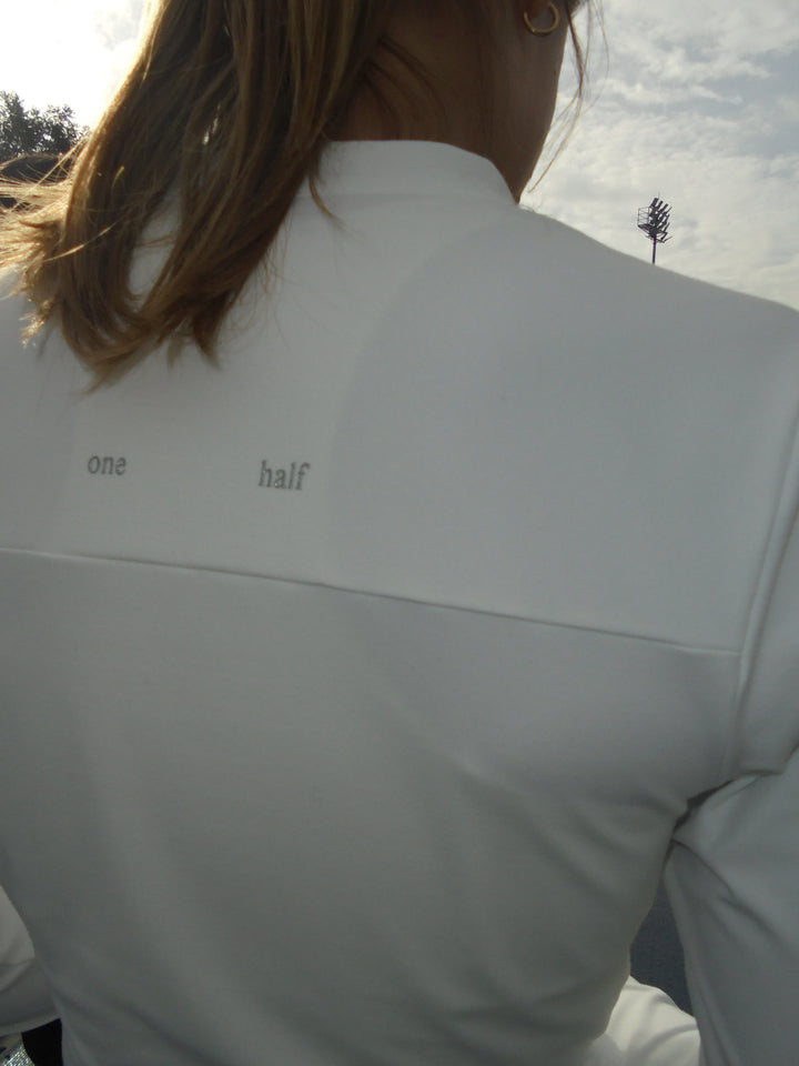 Detalle de la parte posterior de una chaqueta color crema conel logo "one half"