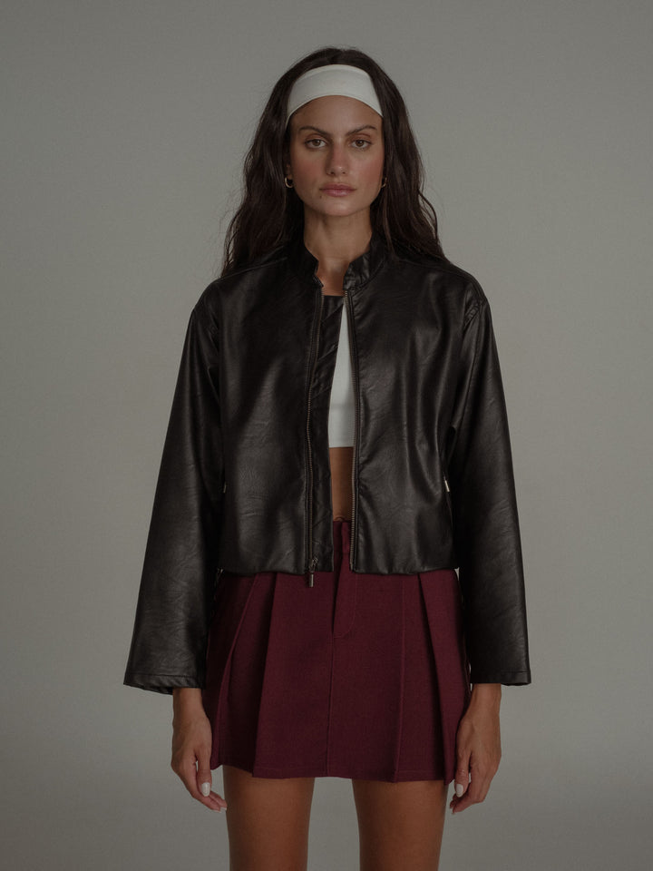 Vista completa de la modelo usando falda, top y chaqueta en cuero