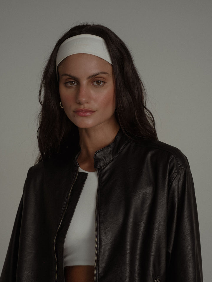 Vista de la parte superior de la modelo usando una chaqueta negra y un top blanco