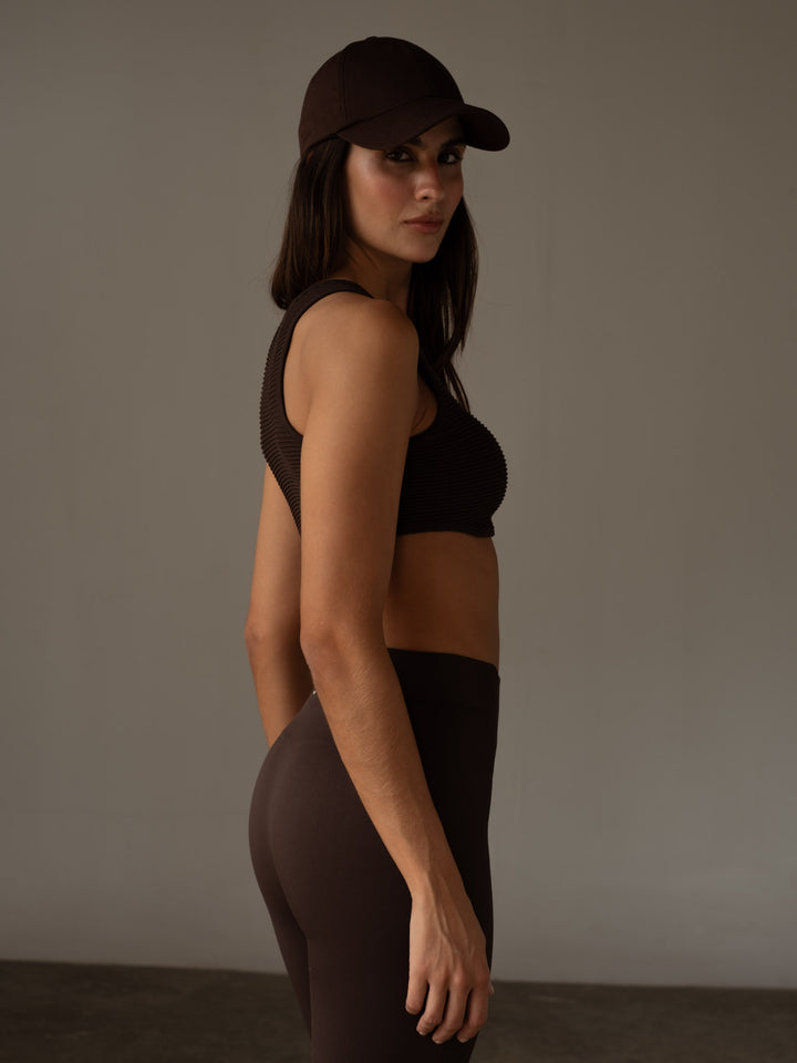 Vista lateral de la modelo usando un conjunto deportivo y una gorra color café
