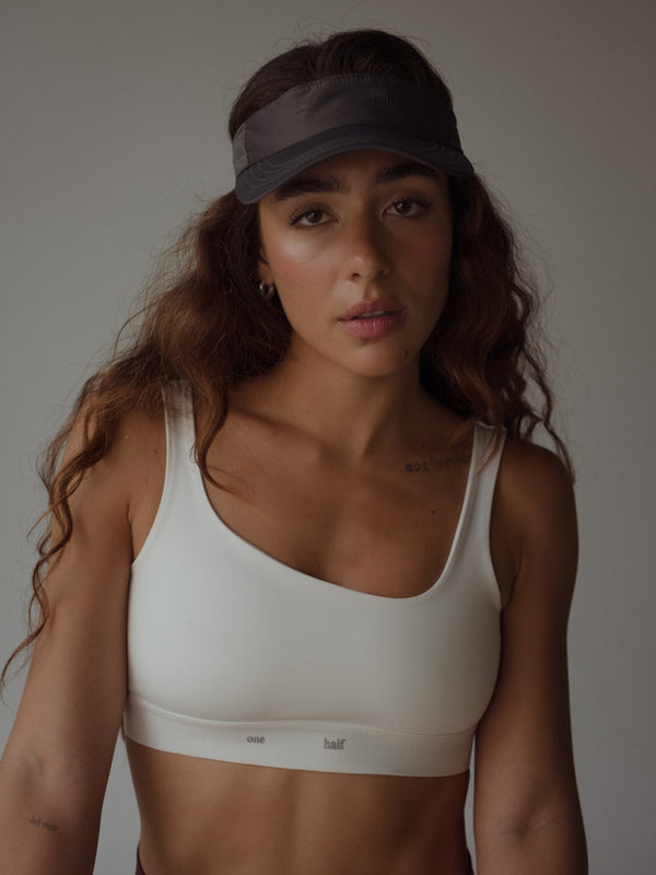 Top deportivo color blanco asimétrico y visera color negro