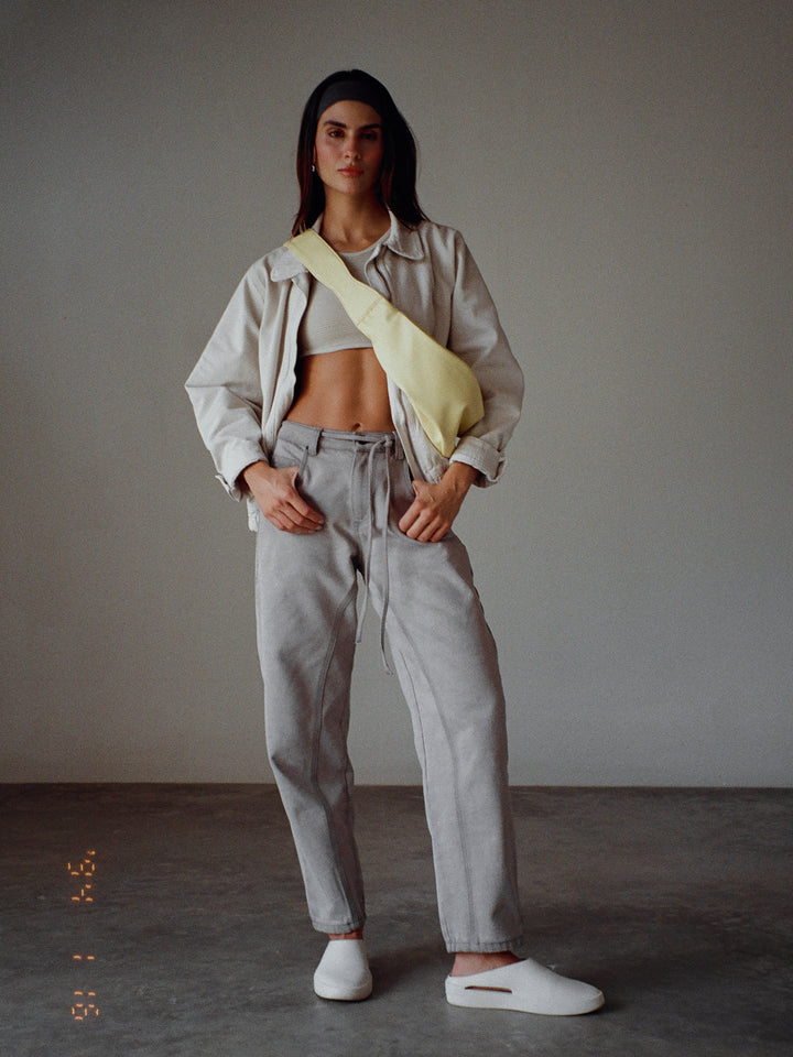 Modelo usando un crop top color gris manga sisa, una chaqueta, un jean y un bolso amarillo