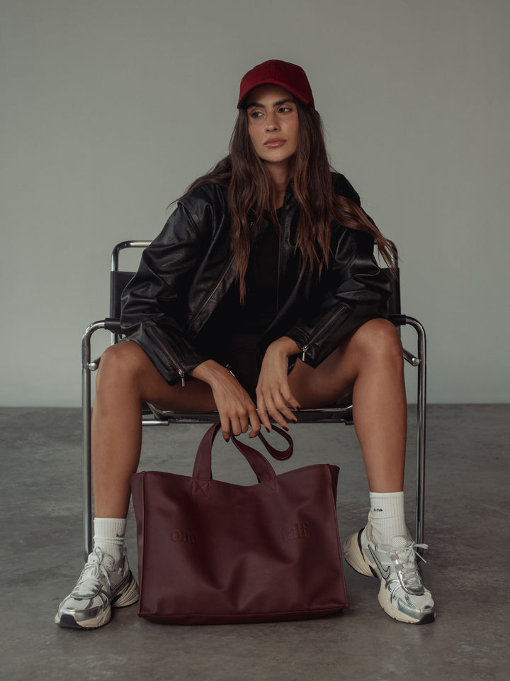 Modelo usando un crop top color negro con una chaqueta, una gorra y un bolso