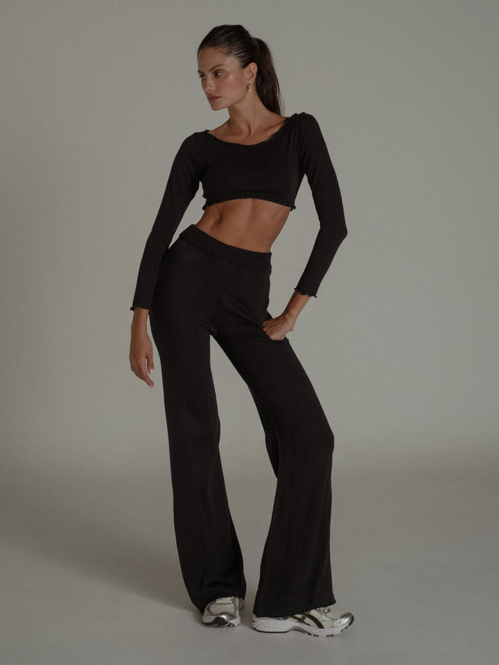 Modelo usando un conjunto negro, crop top y pantalón 