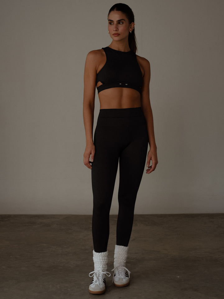 Modelo usando un conjunto deportivo de crop top y leggings color negro y medias largas blancas