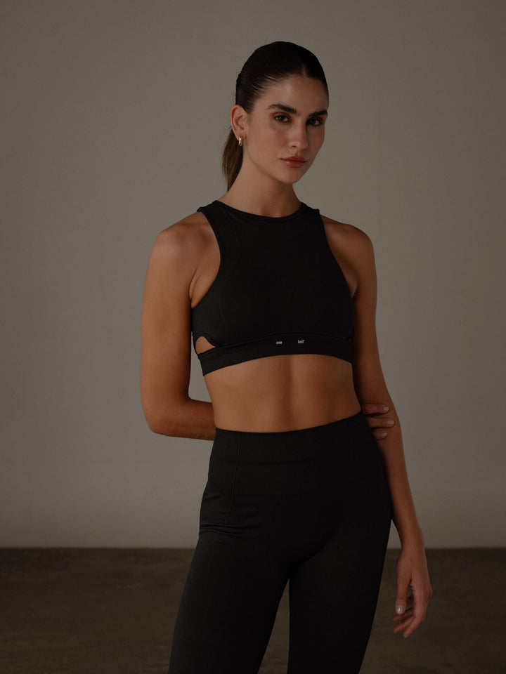 Modelo usando un crop top con aperturas laterales y un leggings color negro