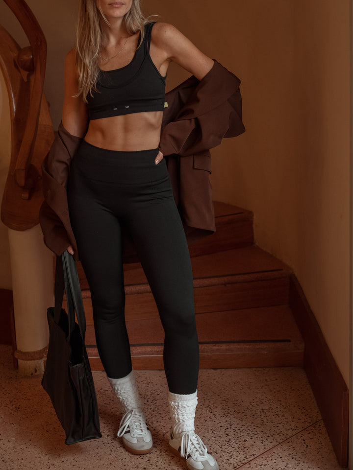 Modelo usando un conjunto deportivo negro, crop top y leggings