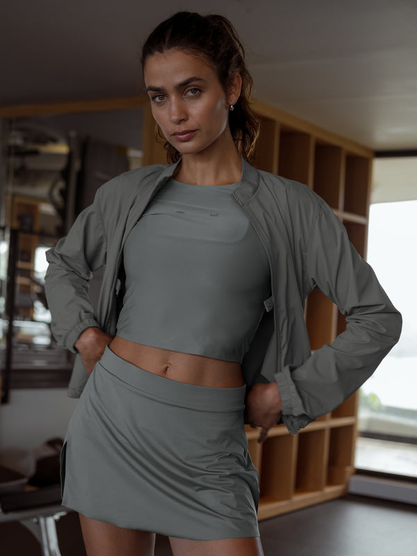 Falda deportiva gris y chaqueta gris abierta sobre top gris