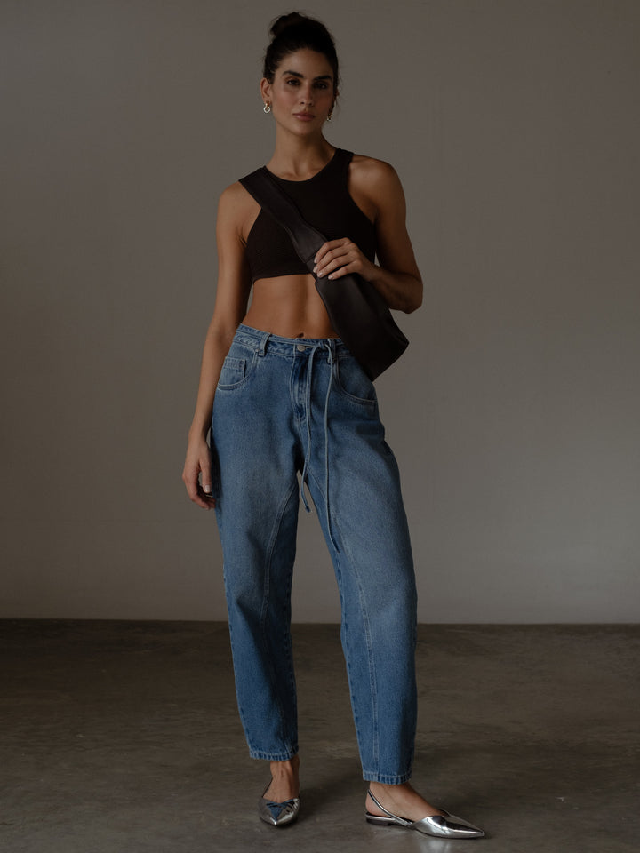 Modelo usando un crop top y un bolso color negro con un Jean color azul