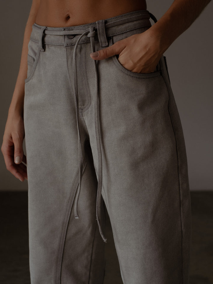 Vista detallada de la parte de la cintura del jean color gris con cordón en denim
