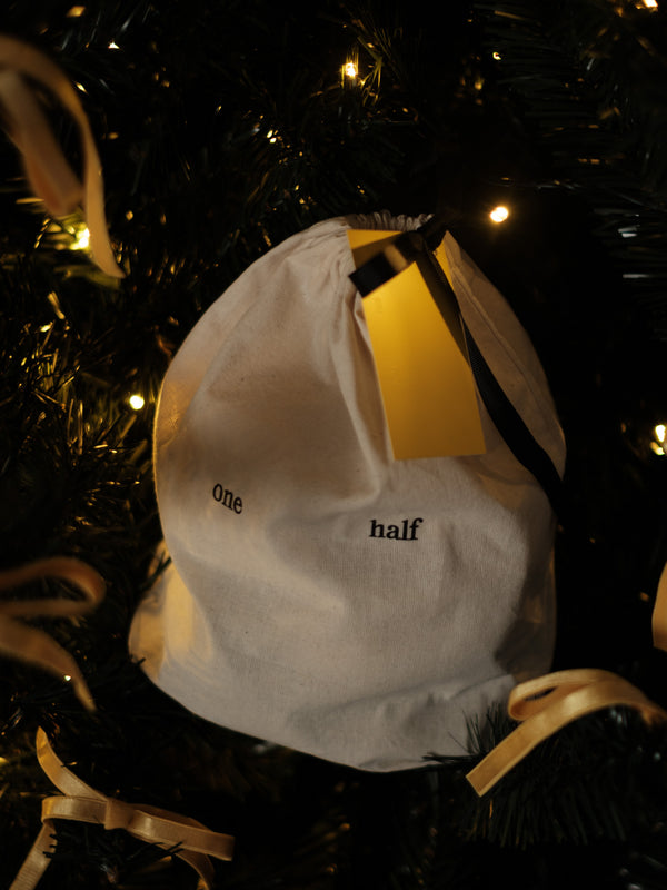 Bolsa de regalo One Half en árbol de navidad con luces. 