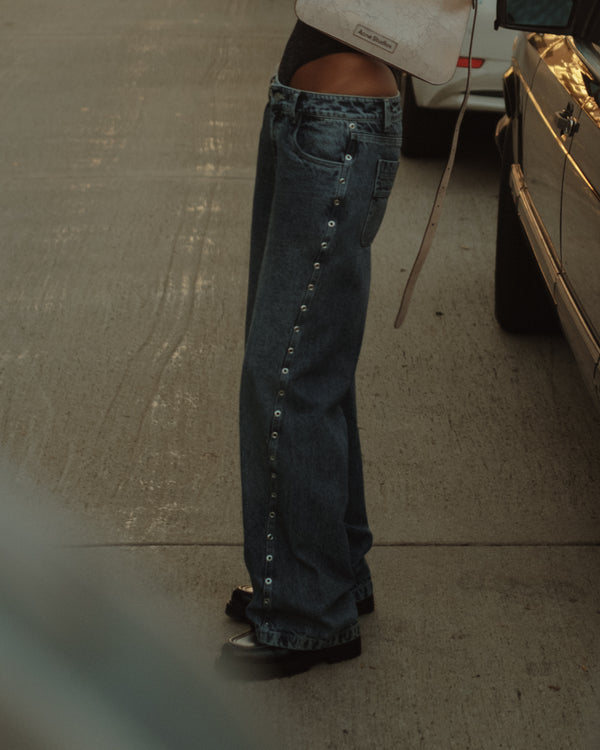 Modelo usando jean azul con apliques metálicos y zapatos negros.