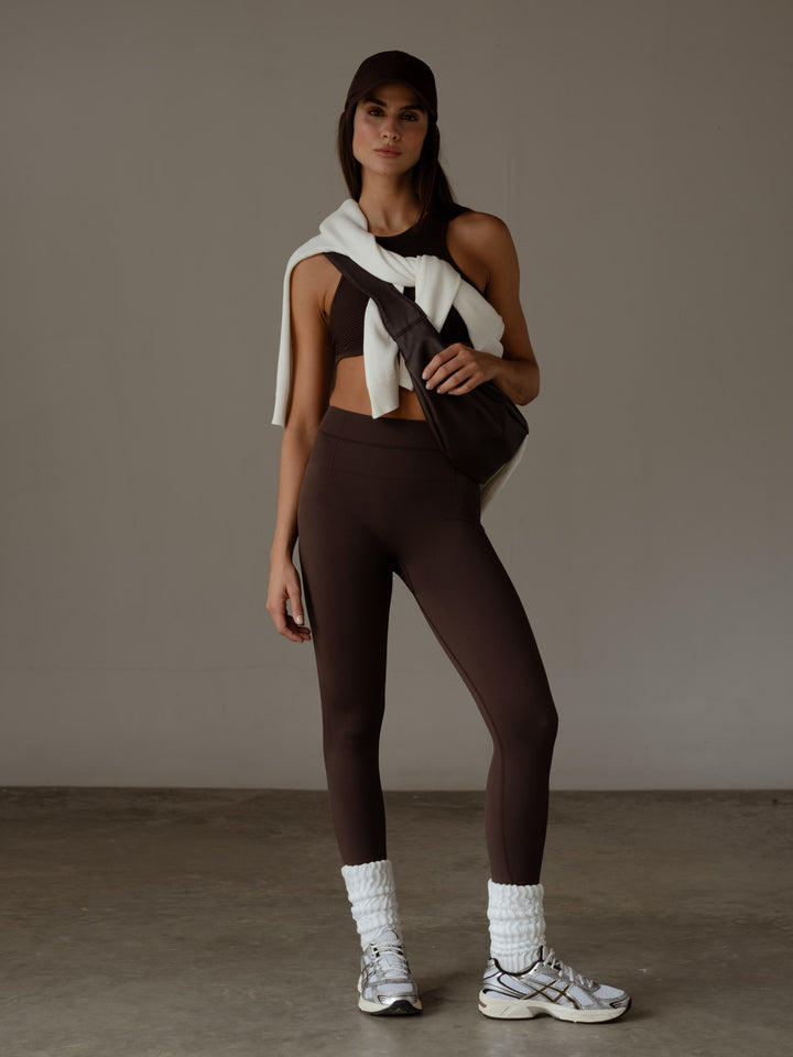 Modelo usando un conjunto deportivo color café con leggings y crop top