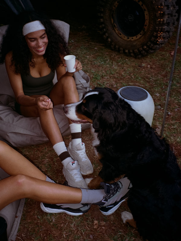 La modelo esta sentada mientras usa conjunto deportivo y medias con raya color verde.