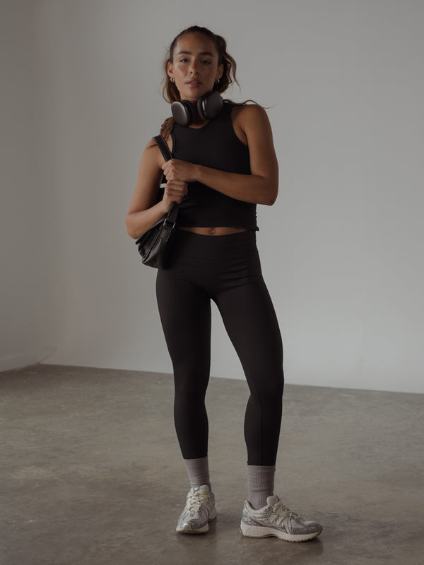 La modelo lleva un conjunto negro,bolso del mismo color y medias media pierna.
