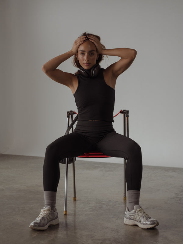 La modelo lleva leggins color negro, crop top del mismo color y medias largas.