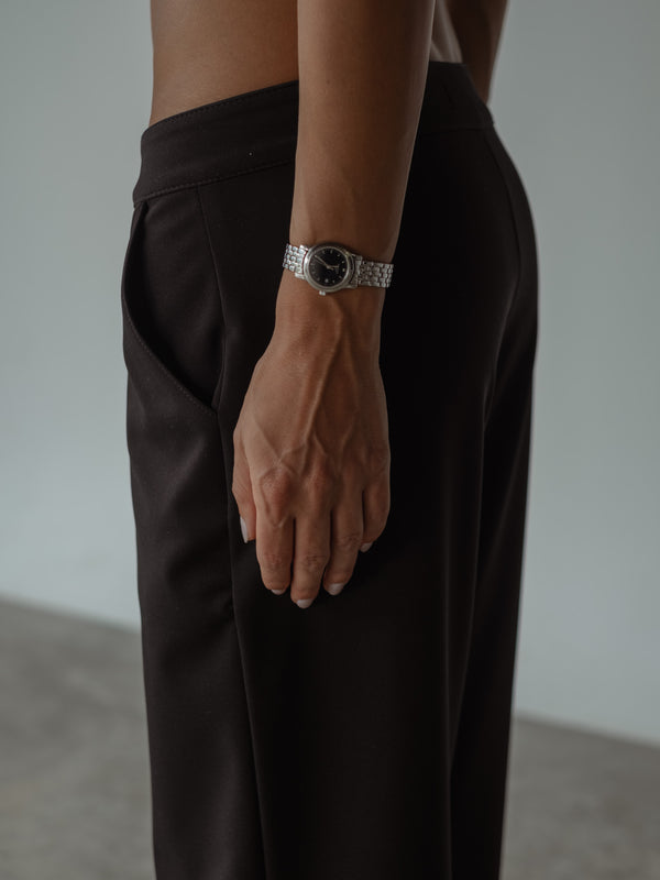 Primer plano lateral de una modelo con un pantalón clásico color negro de tiro medio y bolsillos laterales.