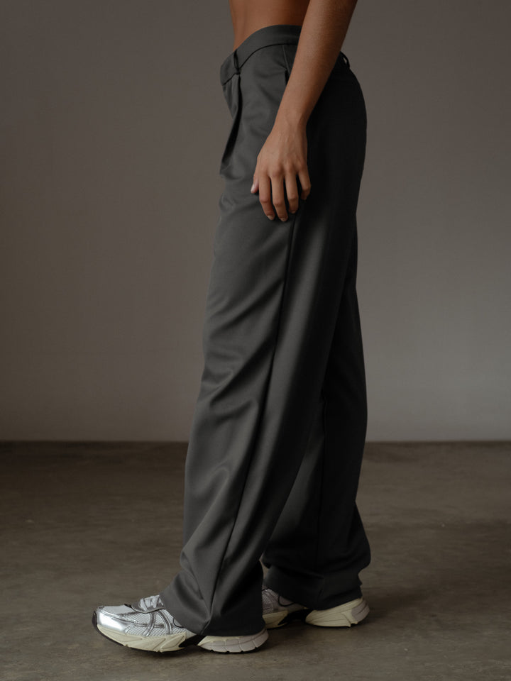 Vista lateral del pantalón plisado color gris con bolsillos laterales y bota recta