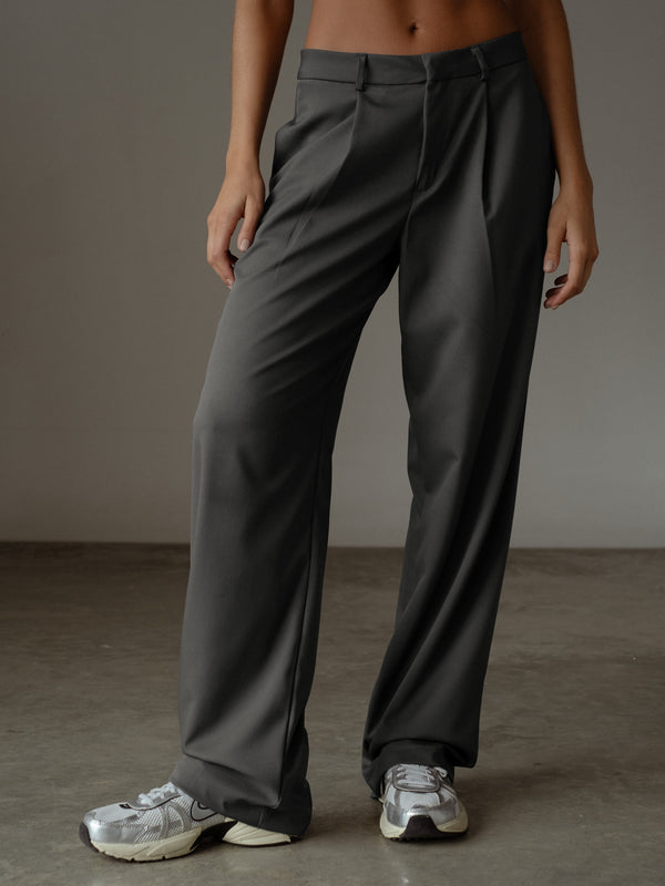 Pantalón plisado color gris en tela fluida, con bolsillos laterales y bota recta