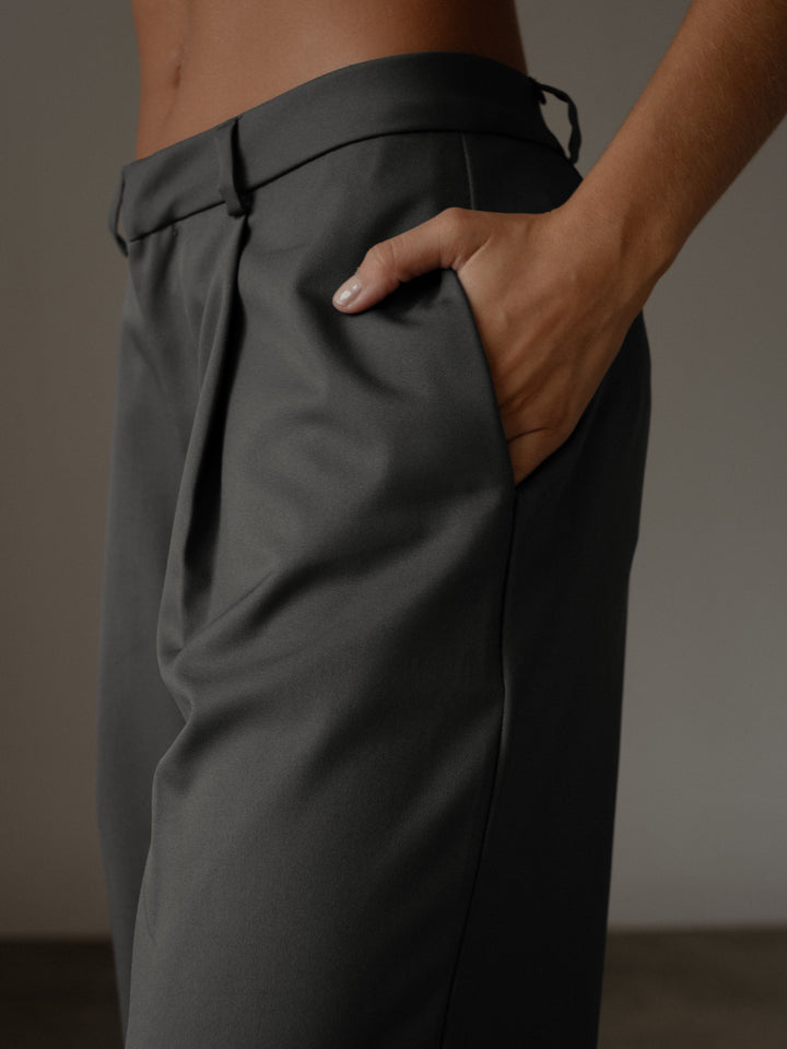 Vista detallada de los bolsillos laterales del pantalón plisado color gris de bota recta