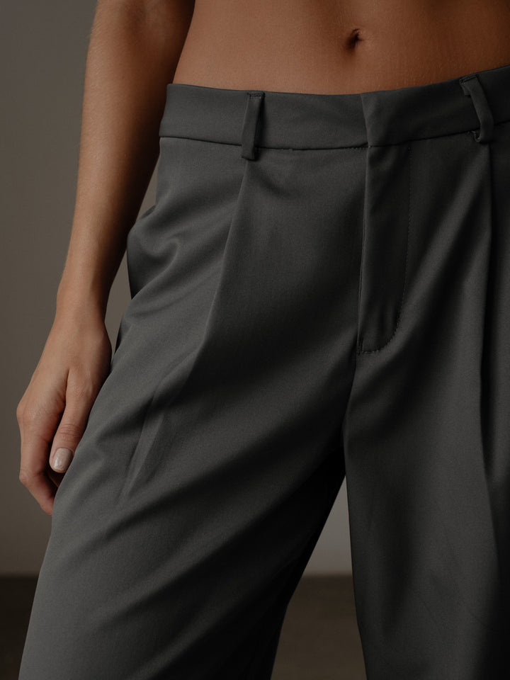 Vista detallada de la cintura del pantalón plisado color gris en tela fluida