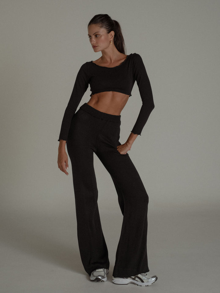 Modelo usando un conjunto negro de crop top y pantalón tejido ancho