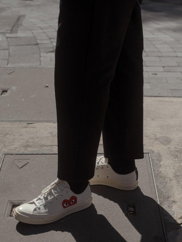 Modelo usando pantalón negro tobillero, medias color negro y zapatos color blanco