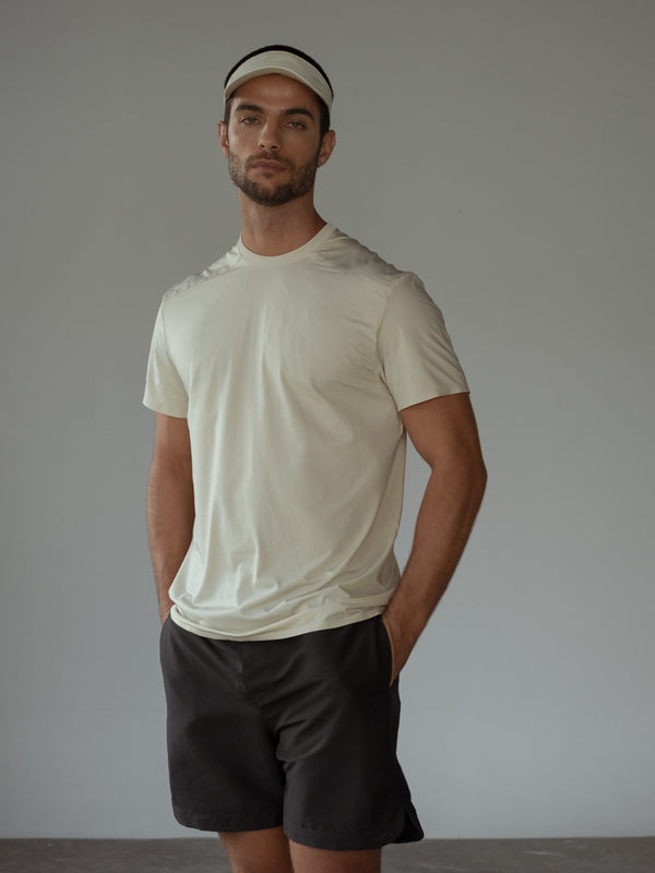 Modelo usando camiseta manga corta color crema, visera y pantaloneta negra