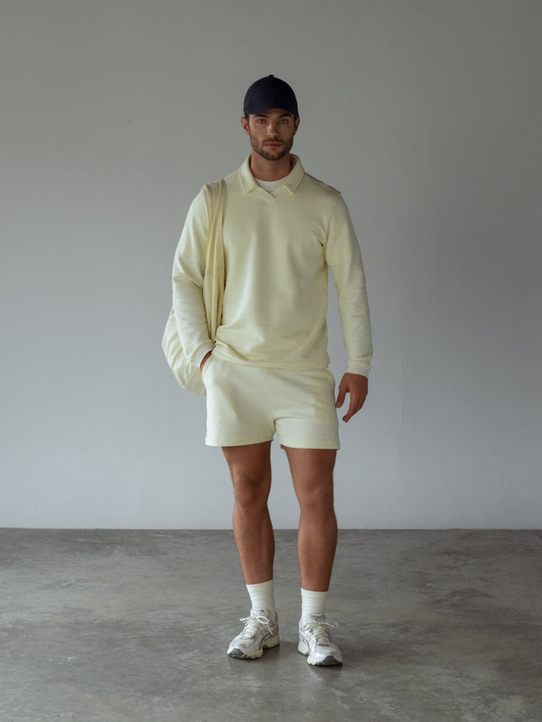 Set deportivo color crema, bolso del mismo color y gorra azul oscuro 