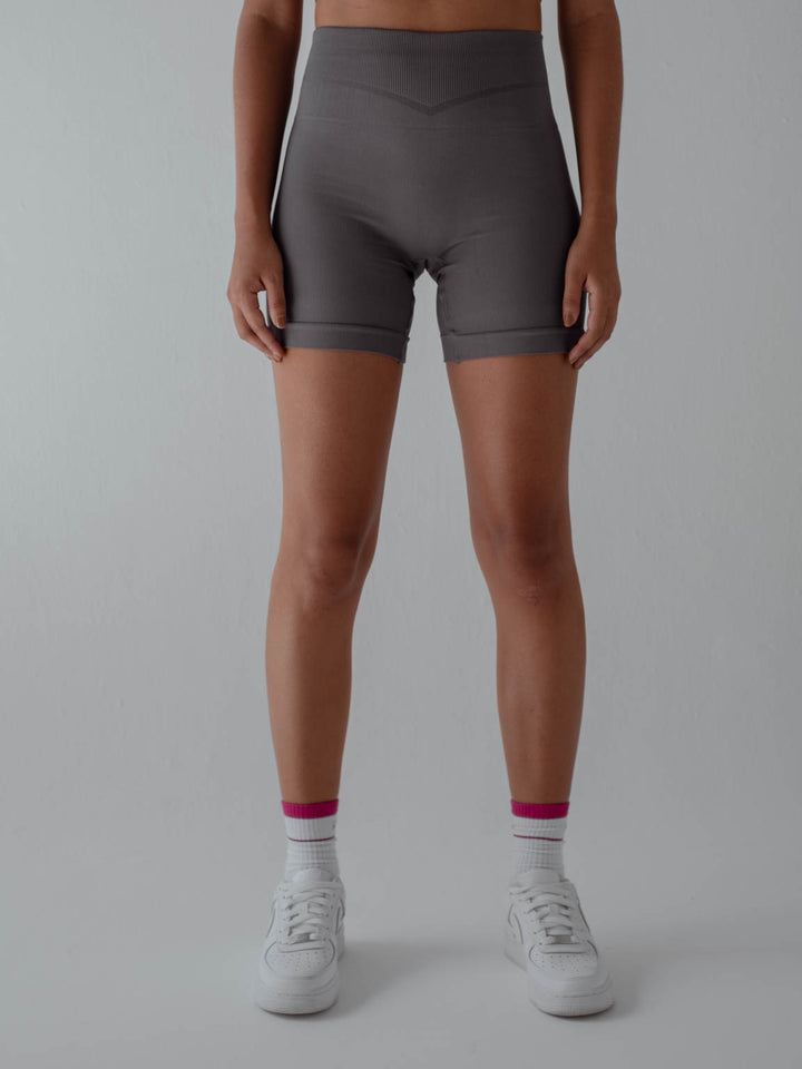 La modelo está usando short deportivo gris con medias color crudo de rayas rosadas.