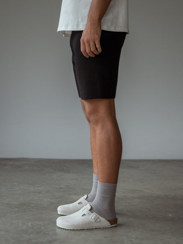 Modelo usando una bermuda color negro y unas medias largas gris claro.