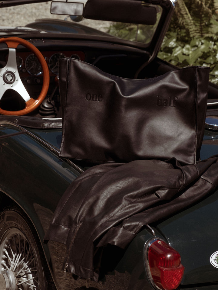 Tote bag en cuero sintético con "One Half" grabado en la parte frontal sobre un auto