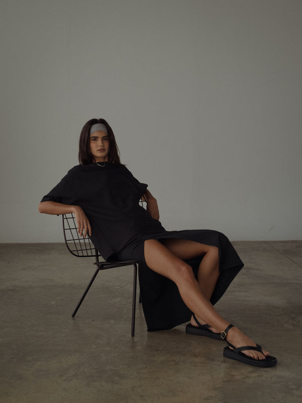 Vista completa de la modelo usando look casual negro, con sandalias y banda para el cabello gris